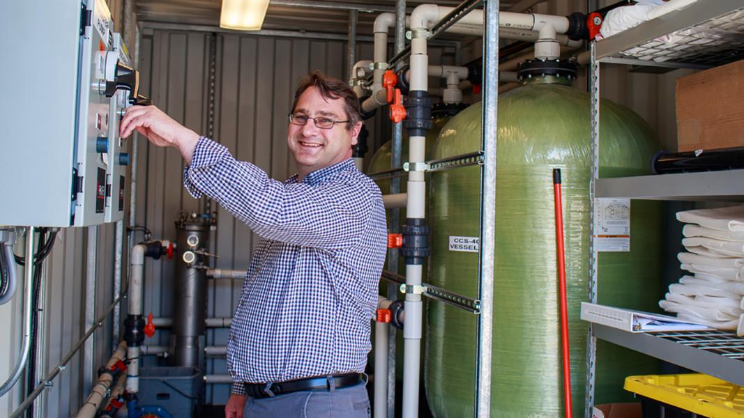 Maxim Petroleum employee smiles at the camera as he flips switches in a control room