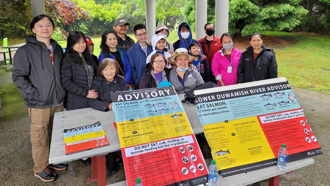 CHAs and community members standing new fish advisory signage.