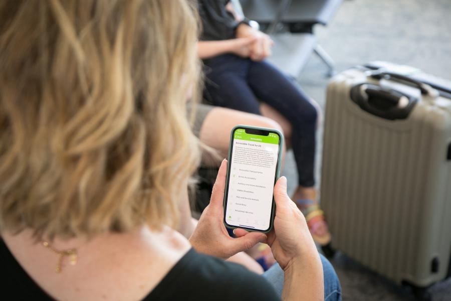 A traveler using the FlySEA App to explore accessibility services at the airport.