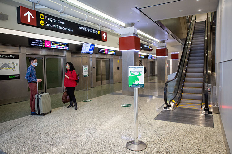 Masked passengers waiting for satellite train at SEA Airport