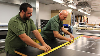 Sign Painter Jayme Harris and Sign Painter Crew Chief Neil Sherk print the sign and prepare it for mounting.